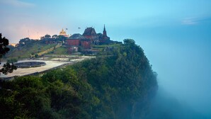A large, historic building with traditional architecture, situated on a lush, green hill. - Thansur Sokha Hotel (Kampot)