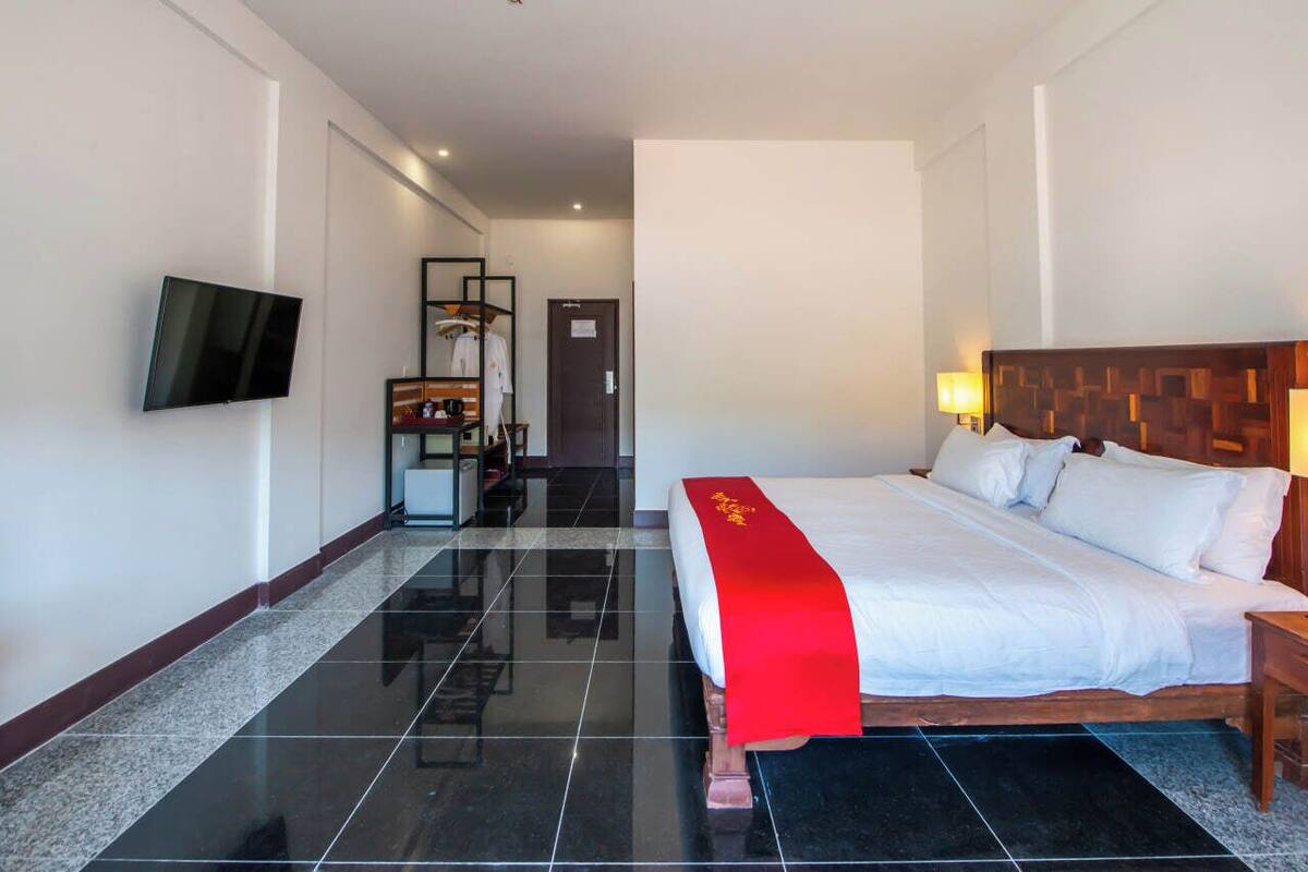 A hotel room with a large bed, a flat-screen TV mounted on the wall, a wardrobe, and a mirror.