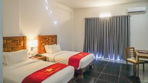 A hotel room with two beds, a desk, a chair, and an air conditioning unit. - Thansur Sokha Hotel (Kampot)