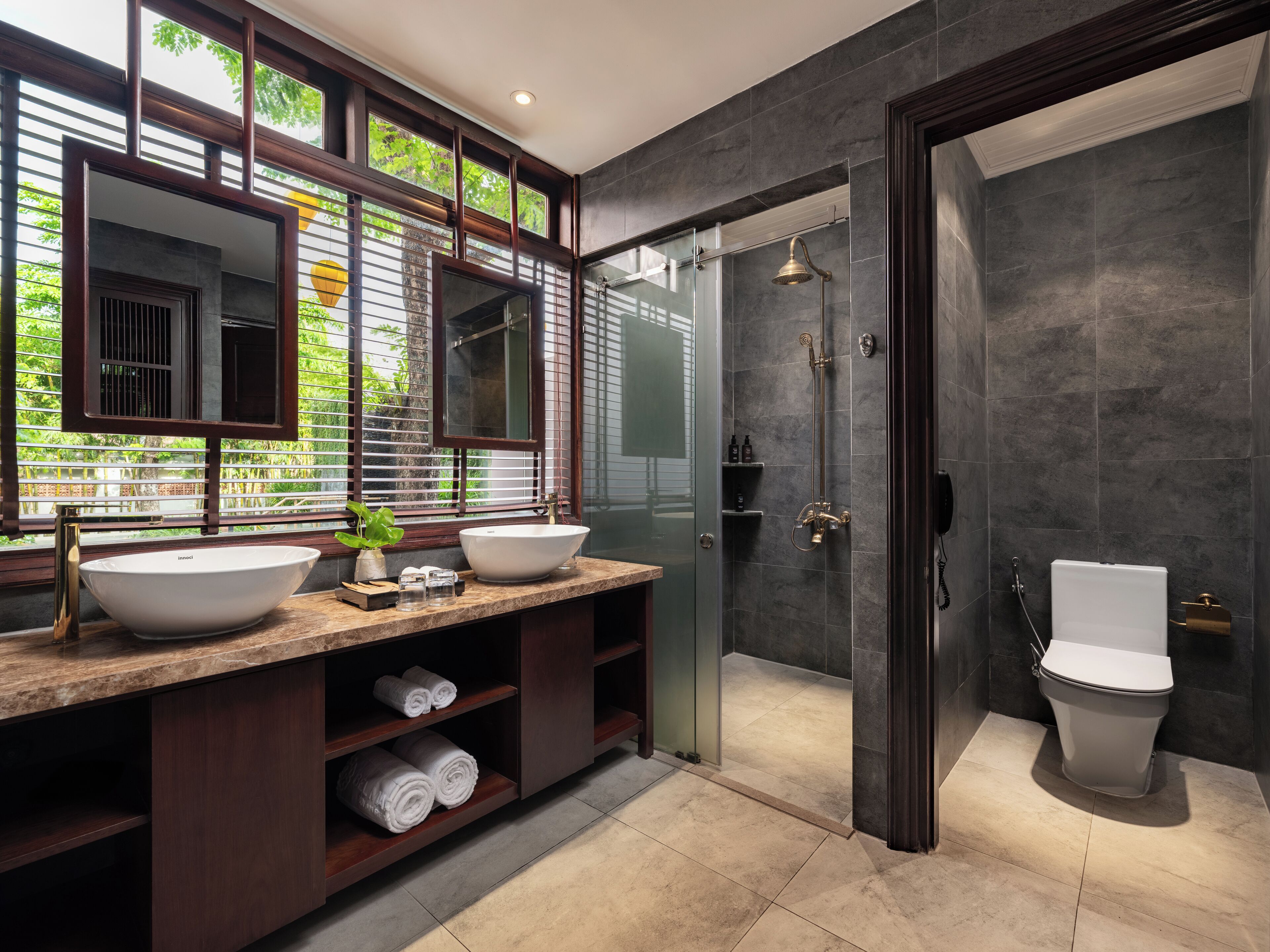 Une salle de bain moderne avec un grand miroir, deux lavabos, une douche et des toilettes.
