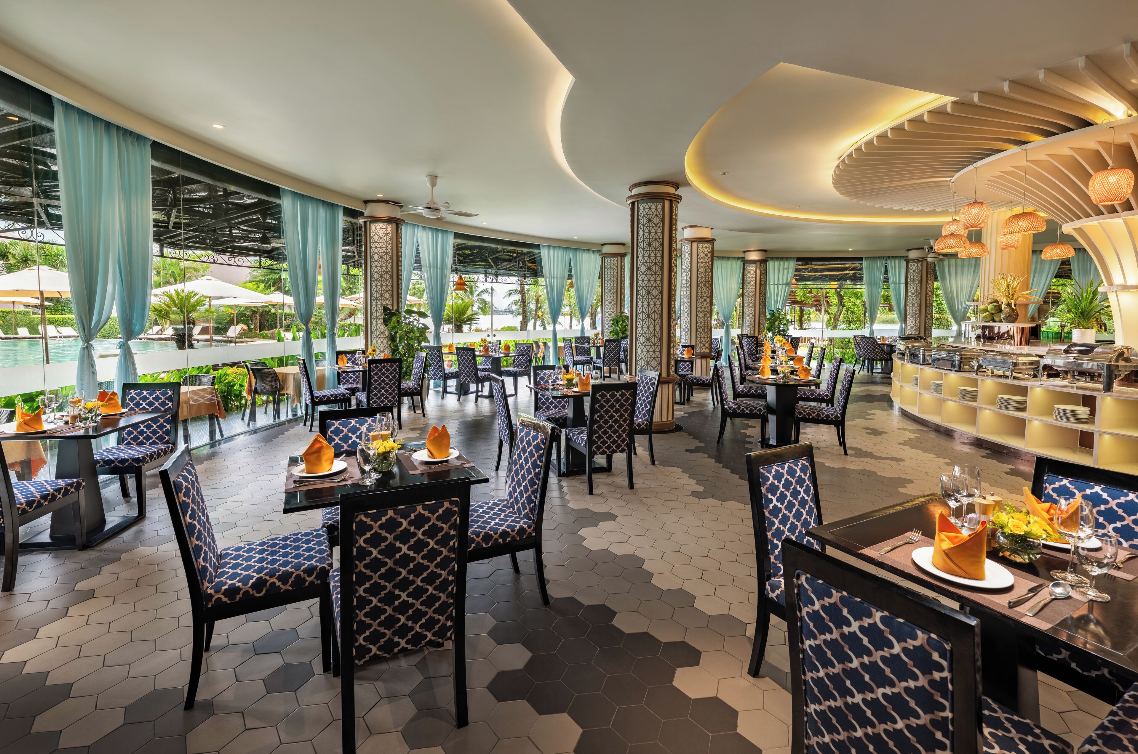 A spacious indoor dining area with hexagonal patterned flooring, blue and white patterned chairs, and a bar area with a curved ceiling.