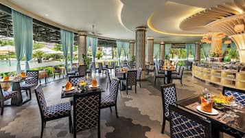 A spacious indoor dining area with hexagonal patterned flooring, blue and white patterned chairs, and a bar area with a curved ceiling.