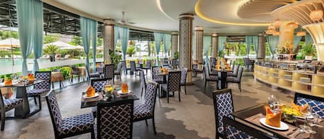 A spacious indoor dining area with hexagonal patterned flooring, blue and white patterned chairs, and a bar area with a curved ceiling.