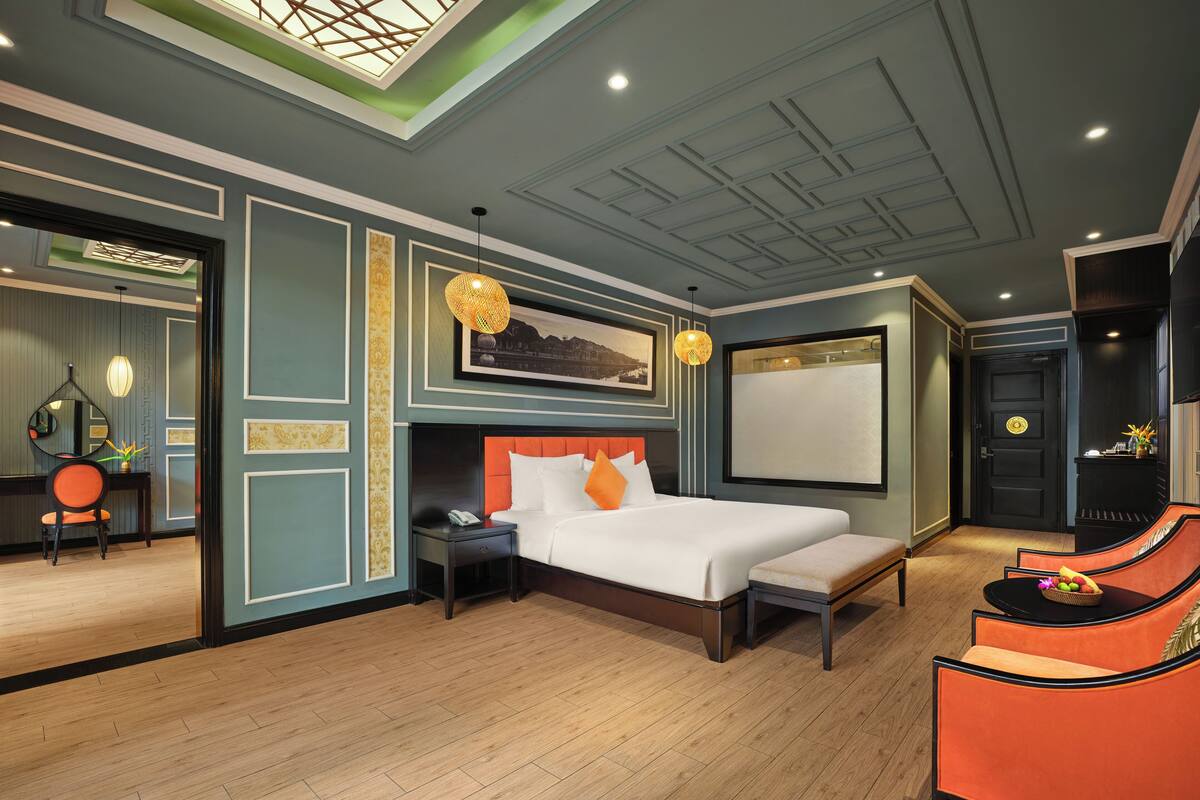 A modern hotel room with a large bed, a desk, and a seating area.