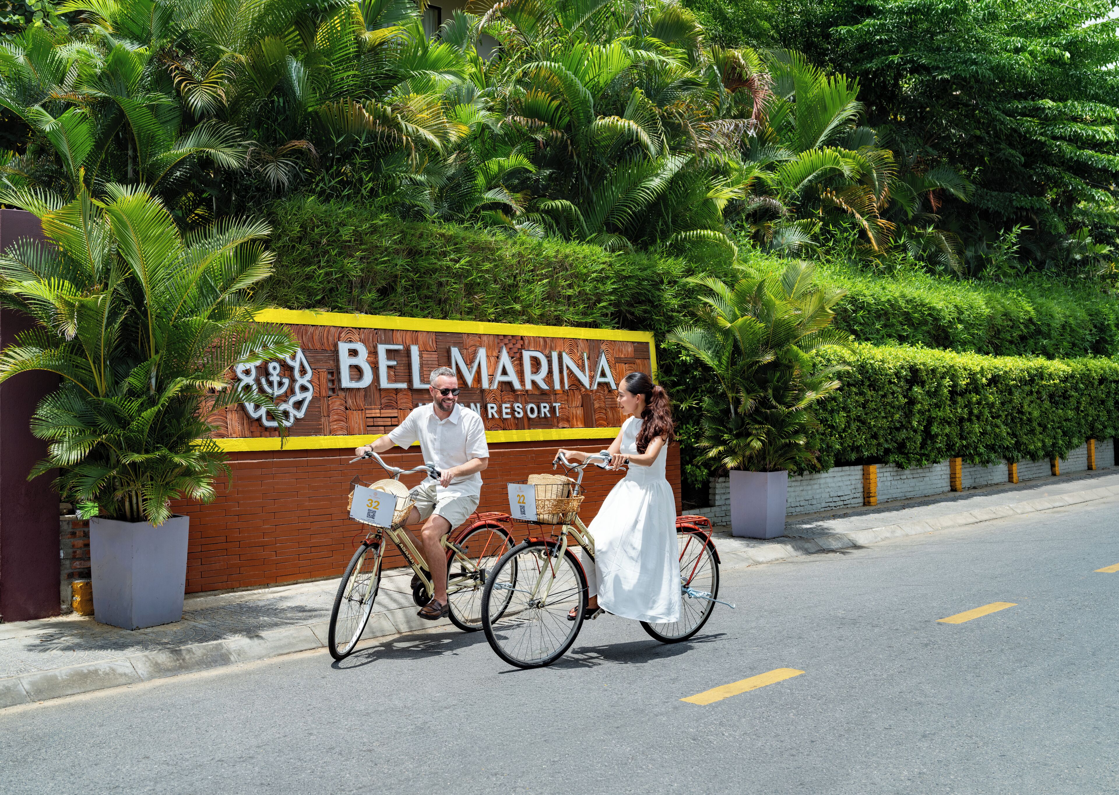 Schild für das Belmarina Resort mit Backsteinmauer und üppiger Bepflanzung.