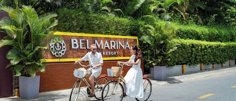 Schild für das Belmarina Resort mit Backsteinmauer und üppiger Bepflanzung.