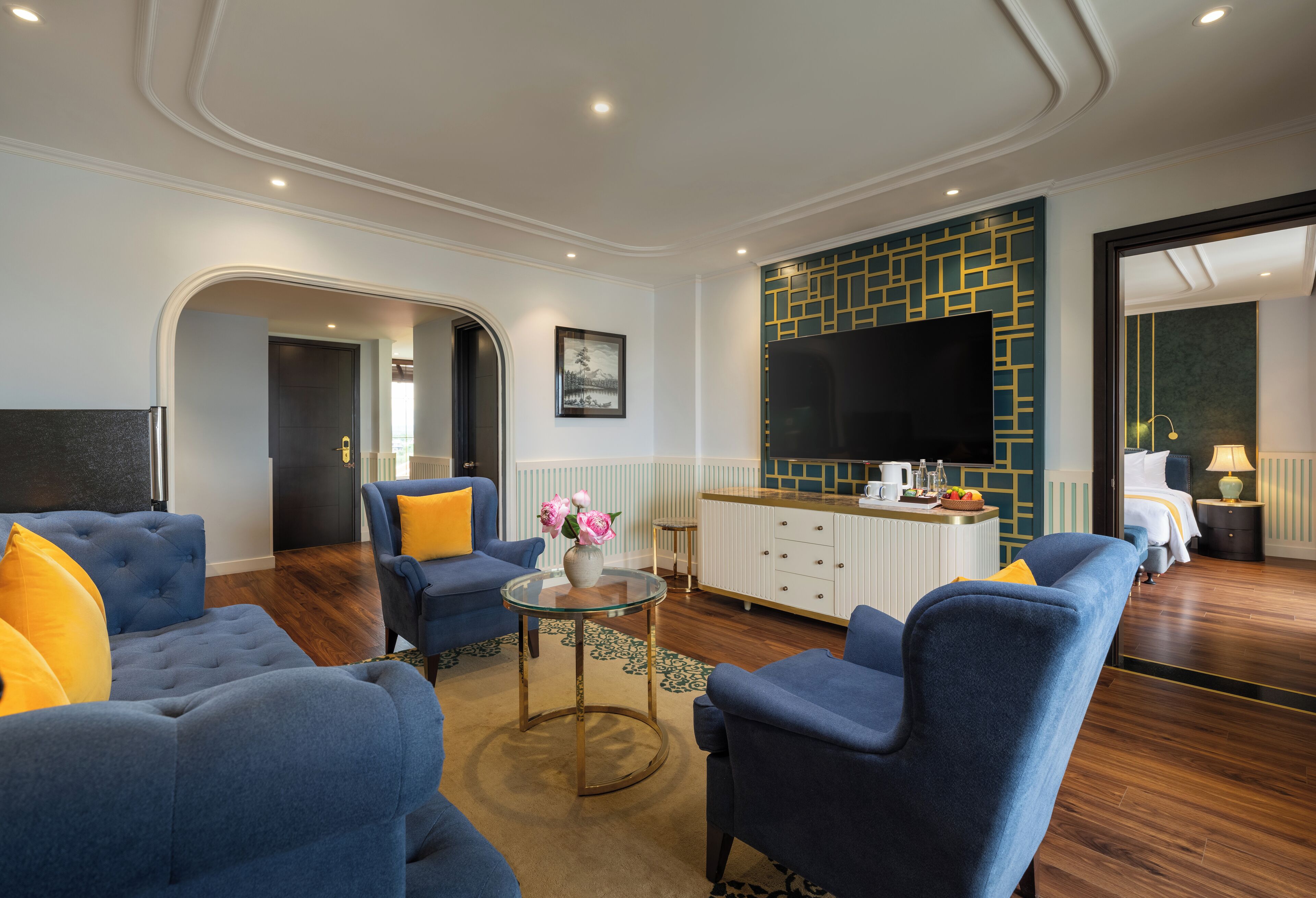 A modern living room with blue sofas, a glass coffee table, and a flat-screen TV.