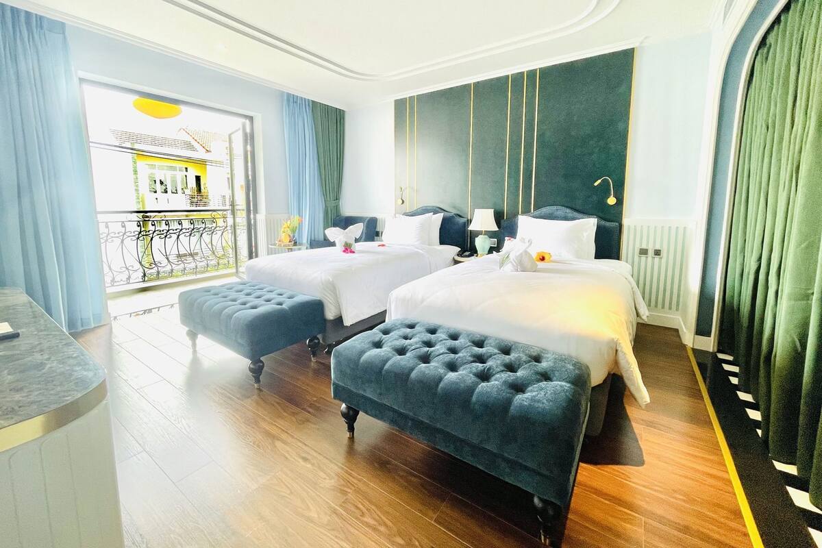 A hotel room with two beds, a sitting area, a view of the outside, and a balcony.