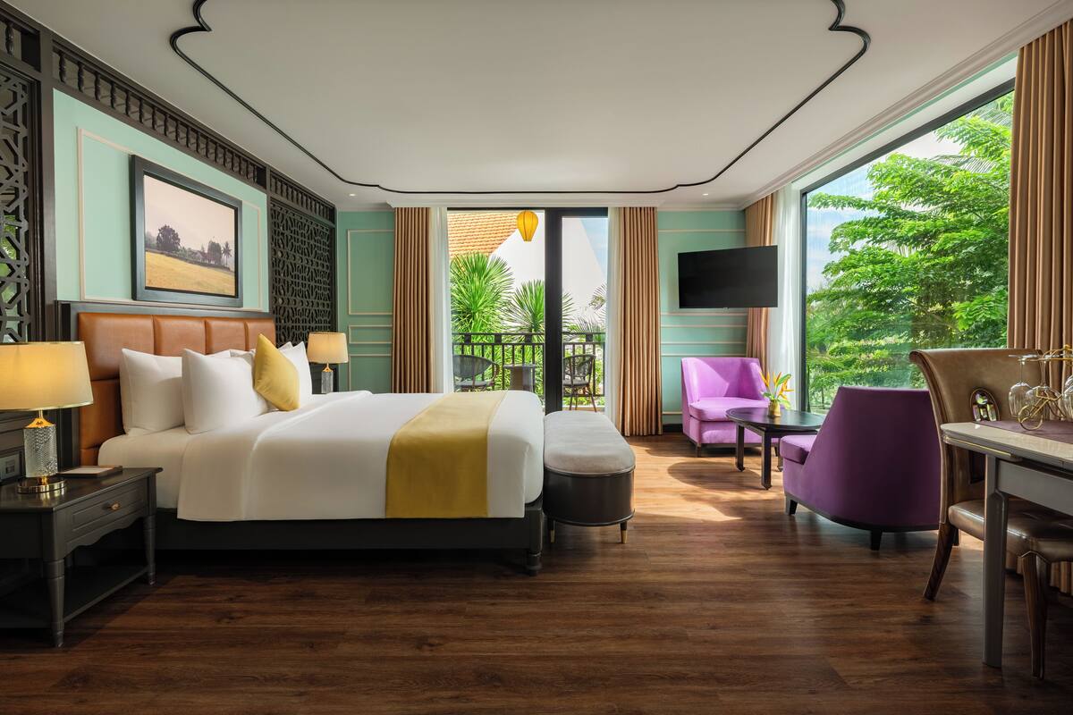 A hotel room with a large bed, a desk, a chair, and a TV.