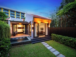 Uma casa moderna com um pátio, uma área de refeições e uma escadaria visível que leva à entrada.