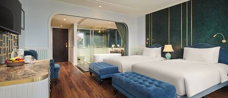 A modern hotel room with two beds, a sitting area with a coffee table, and a view of the city through a glass door.