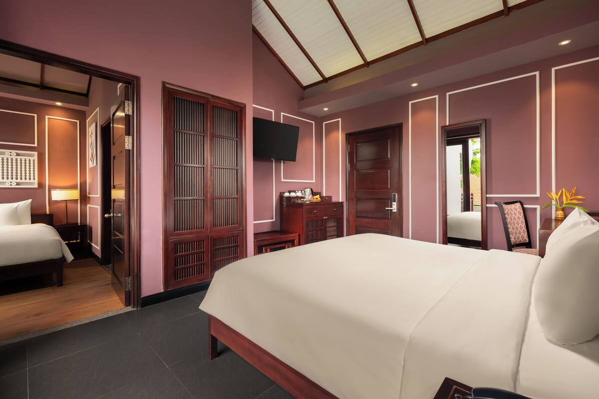 A modern hotel room with a large bed, a desk, a TV, and a view of the outdoors.