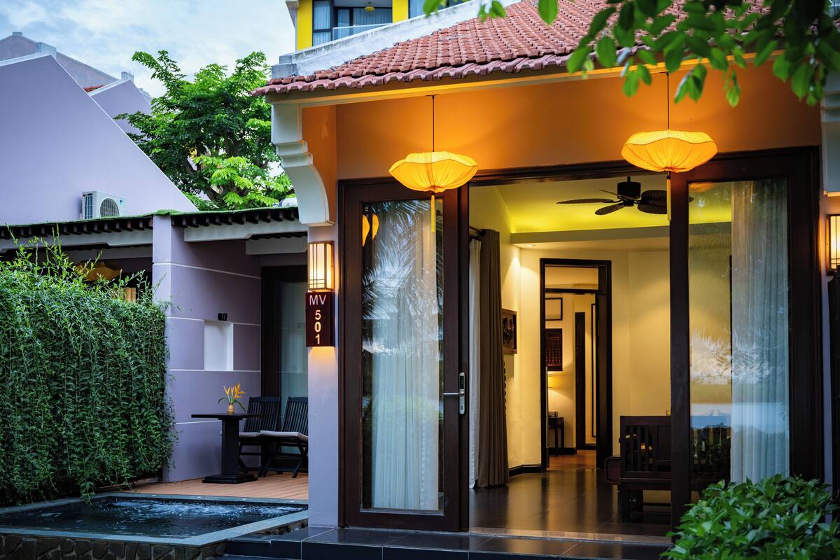 A modern villa with a covered entrance, a hot tub, and a dining area with outdoor seating.