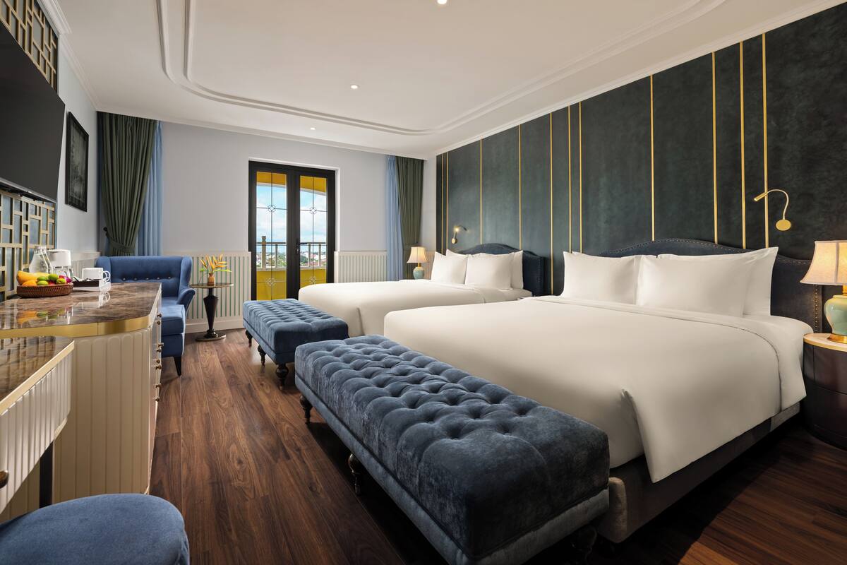 A hotel room with a large bed, two bedside tables, a desk, and a chair.