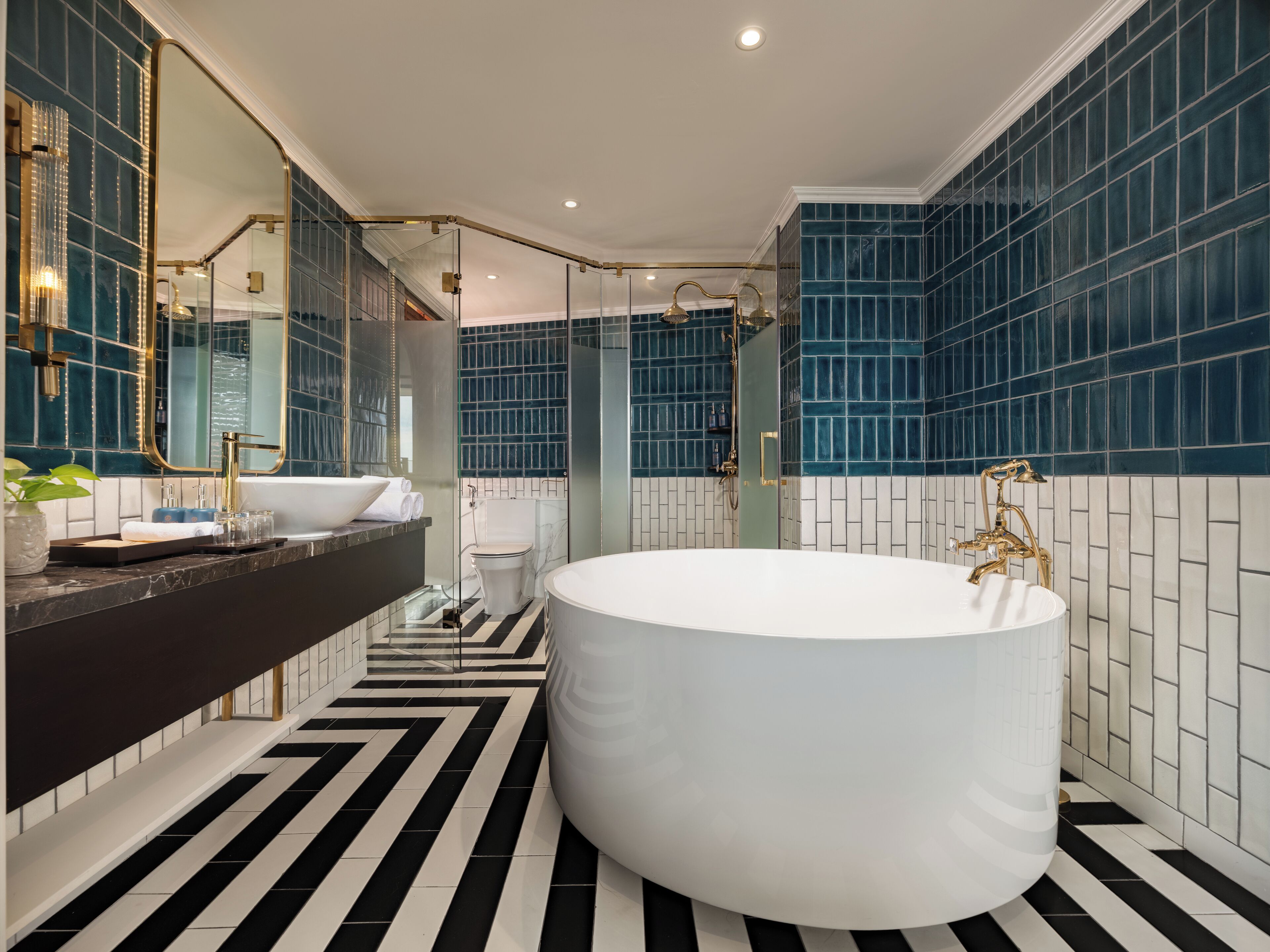Un baño moderno con una bañera grande, piso a rayas negras y blancas y paredes con azulejos azules.