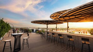 A rooftop bar with wooden flooring, multiple tables and chairs, and large umbrellas providing shade. - Bel Marina Hoi An Resort (Da Nang)