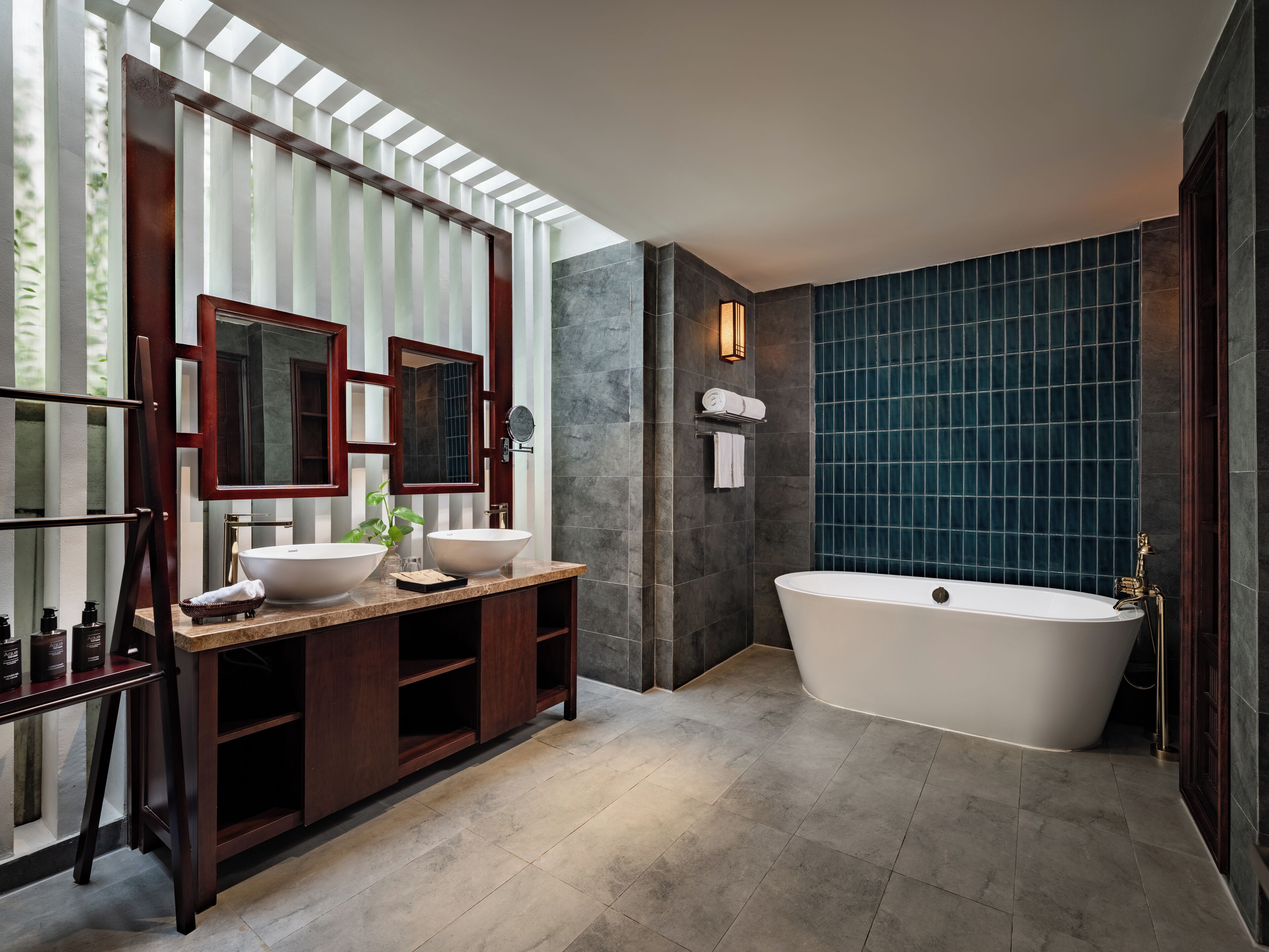 A modern bathroom with a freestanding bathtub, two large sinks, and a vanity with a mirror.