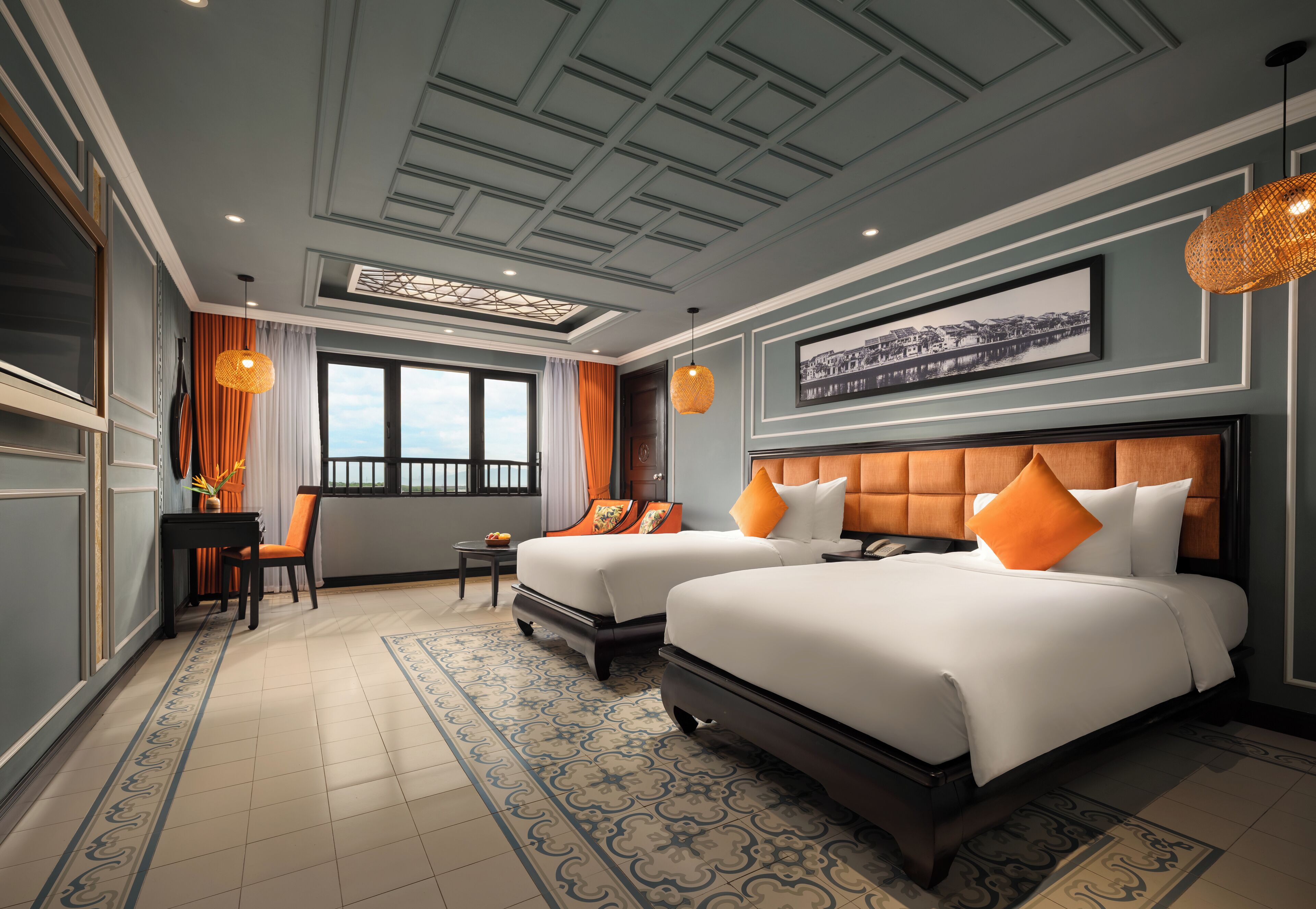 A hotel room with two beds, a desk, and a window with curtains.