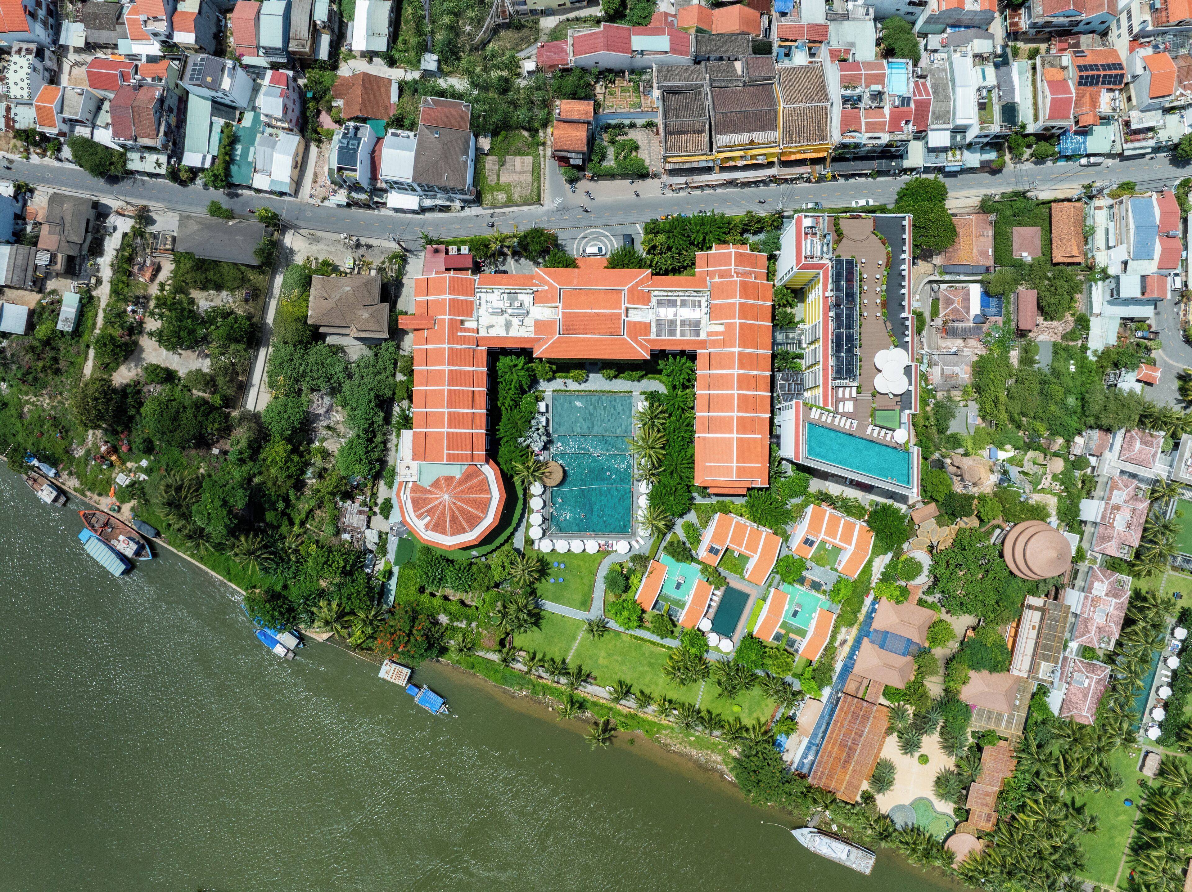 An aerial view of a coastal property with a swimming pool, multiple guest rooms, and a beachfront.