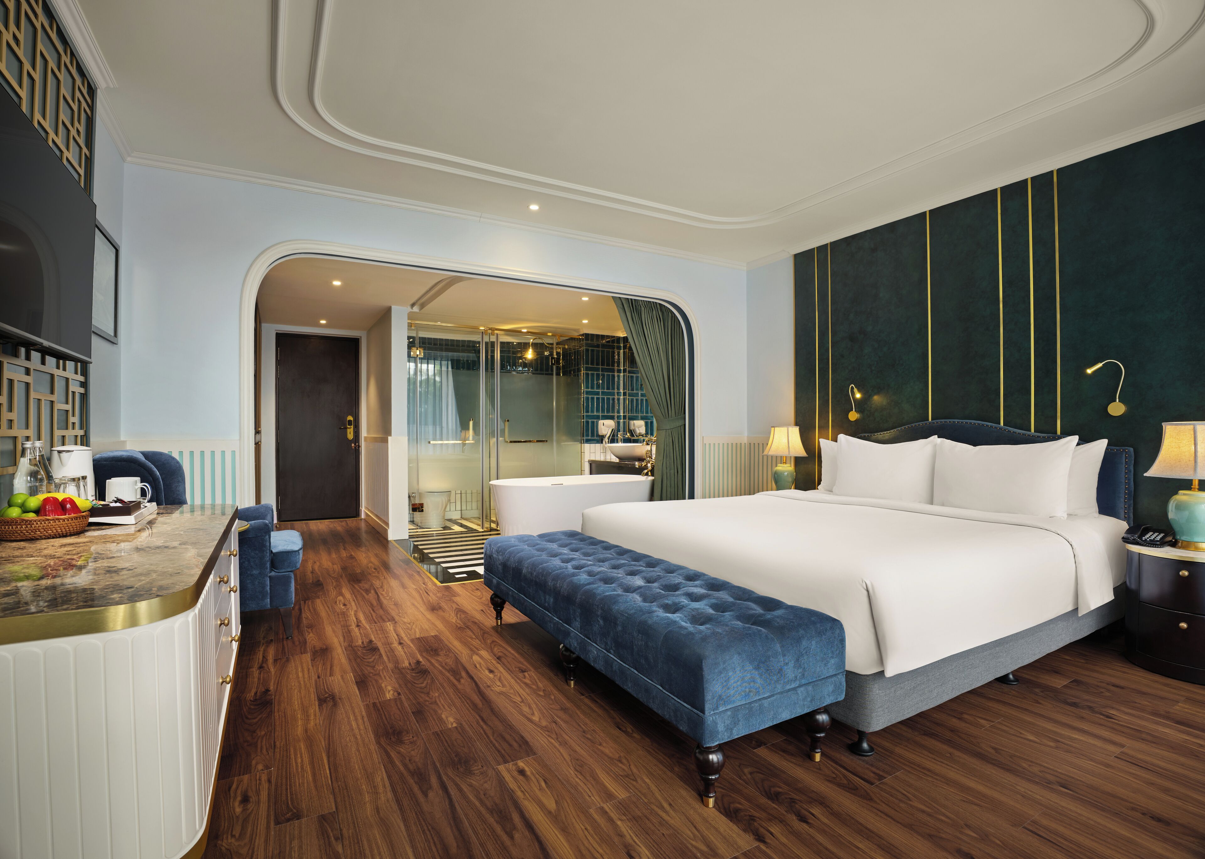 Une chambre d’hôtel moderne dotée d’un grand lit, d’un coin salon, d’une salle de bain avec une douche en verre et offrant une vue sur la ville.