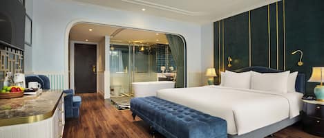 Une chambre d’hôtel moderne dotée d’un grand lit, d’un coin salon, d’une salle de bain avec une douche en verre et offrant une vue sur la ville.