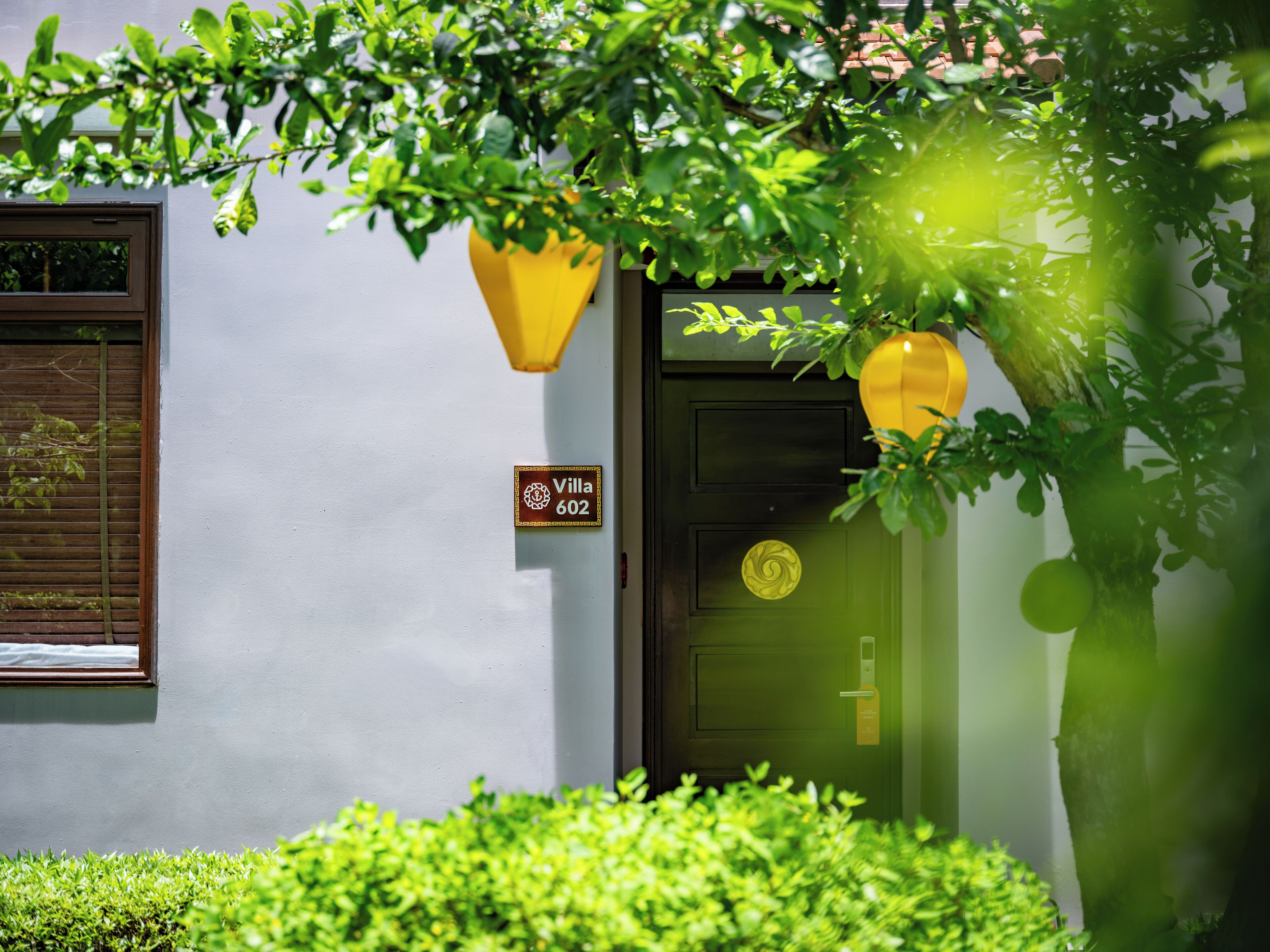 A villa with a door marked "Villa 602," a window with blinds, and a yellow hanging light fixture.