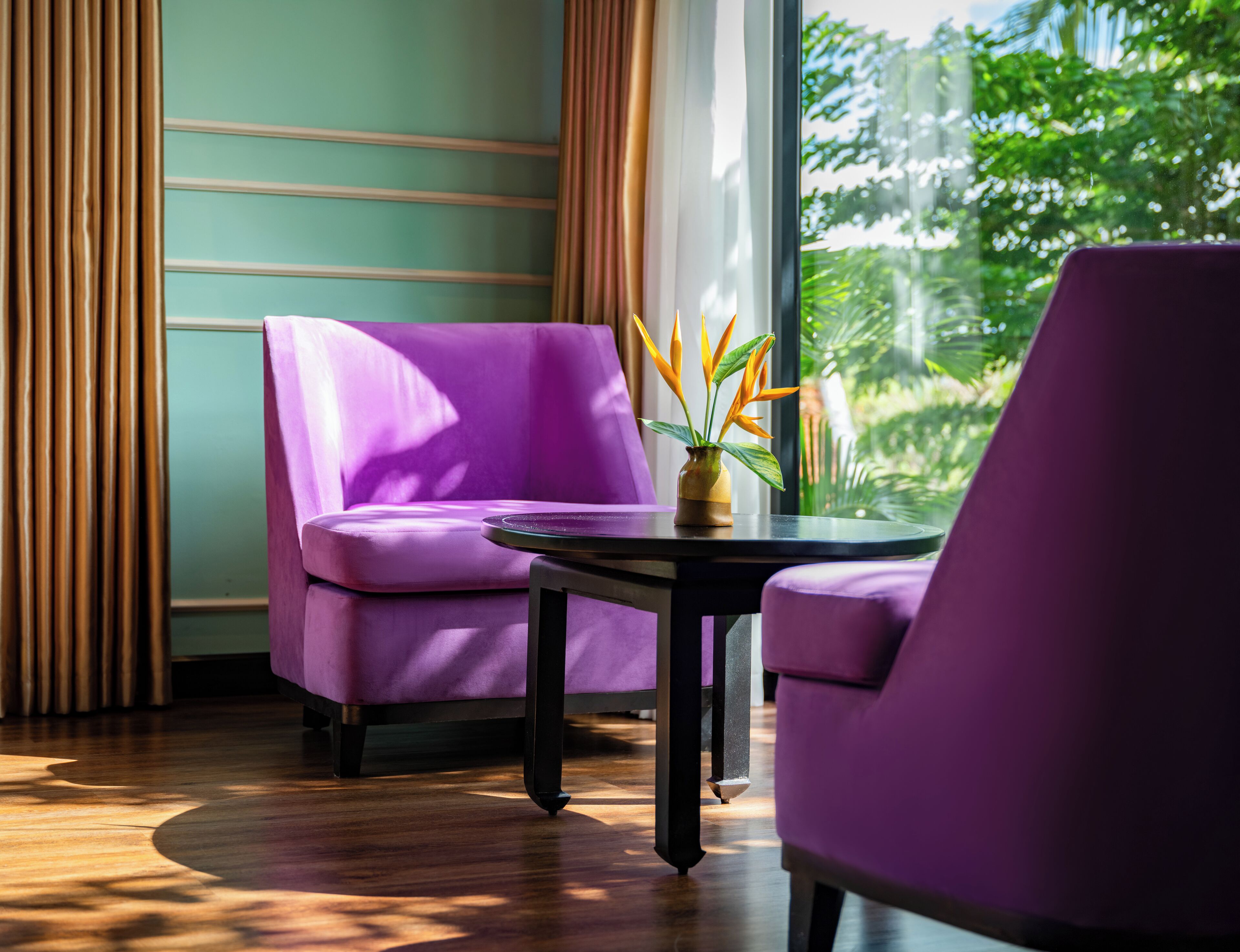Een kamer met een paarse bank, een kleine tafel en een raam met gordijnen.