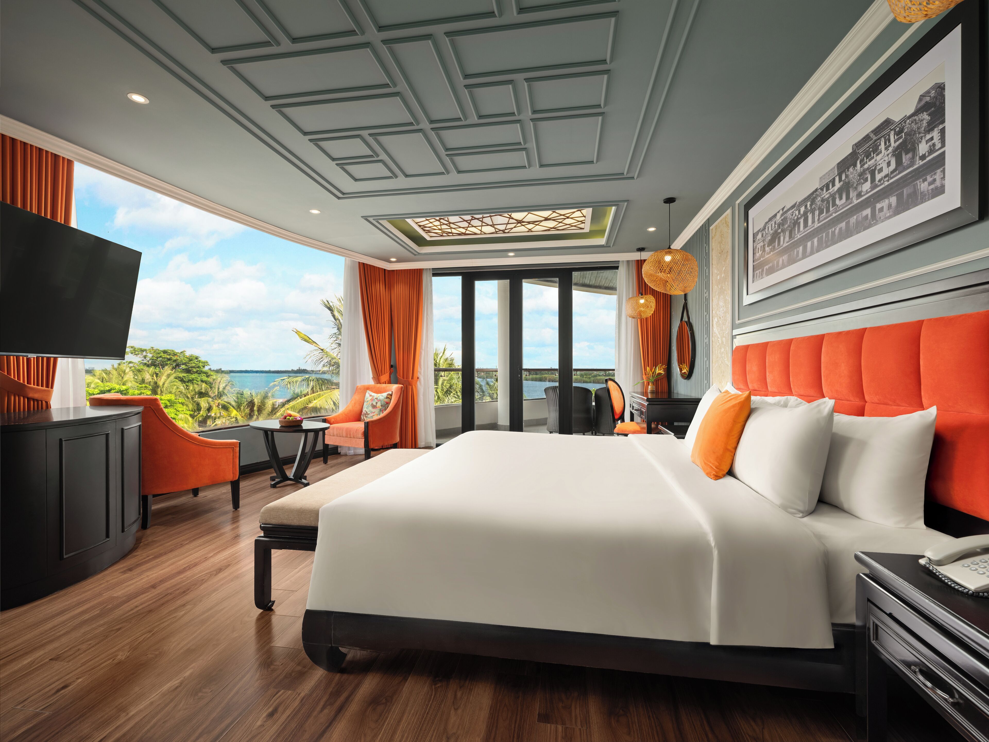 Une chambre d’hôtel moderne dotée d’un grand lit, d’un bureau, d’une télévision et offrant une vue sur l’océan.