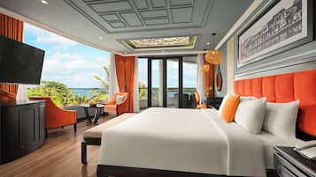 Une chambre d’hôtel moderne dotée d’un grand lit, d’un bureau, d’une télévision et offrant une vue sur l’océan.