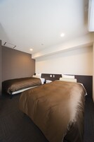Ein Hotelzimmer mit zwei Betten, einem dunklen Teppich und einer weißen Decke mit Einbaustrahlern.