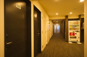 Un pasillo de hotel con puertas numeradas 1309, una máquina expendedora de bebidas y suelo alfombrado.