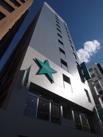 Ein hohes Gebäude mit einer großen sternförmigen Leuchtreklame für das Hotel Urban Central.