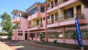 A multi-story building with balconies and large windows, featuring a welcoming sign. - Stella Maris Lodge (Moshi)