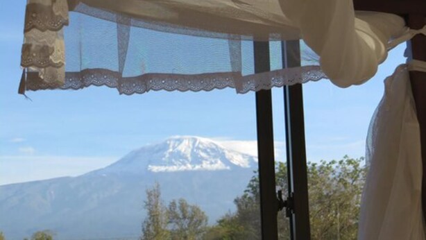 A room with a large window overlooking a snow-capped mountain. - Stella Maris Lodge (Moshi)