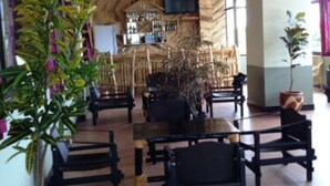 A restaurant with a thatched roof, wooden furniture, and a bar area. - Stella Maris Lodge (Moshi)