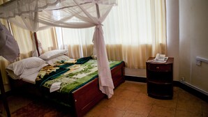 A bedroom with a bed, a nightstand, and a telephone. - Stella Maris Lodge (Moshi)