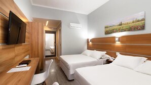 A hotel room with two beds, a desk with a chair, a TV, and a painting on the wall. - Hotel KK (Itu)