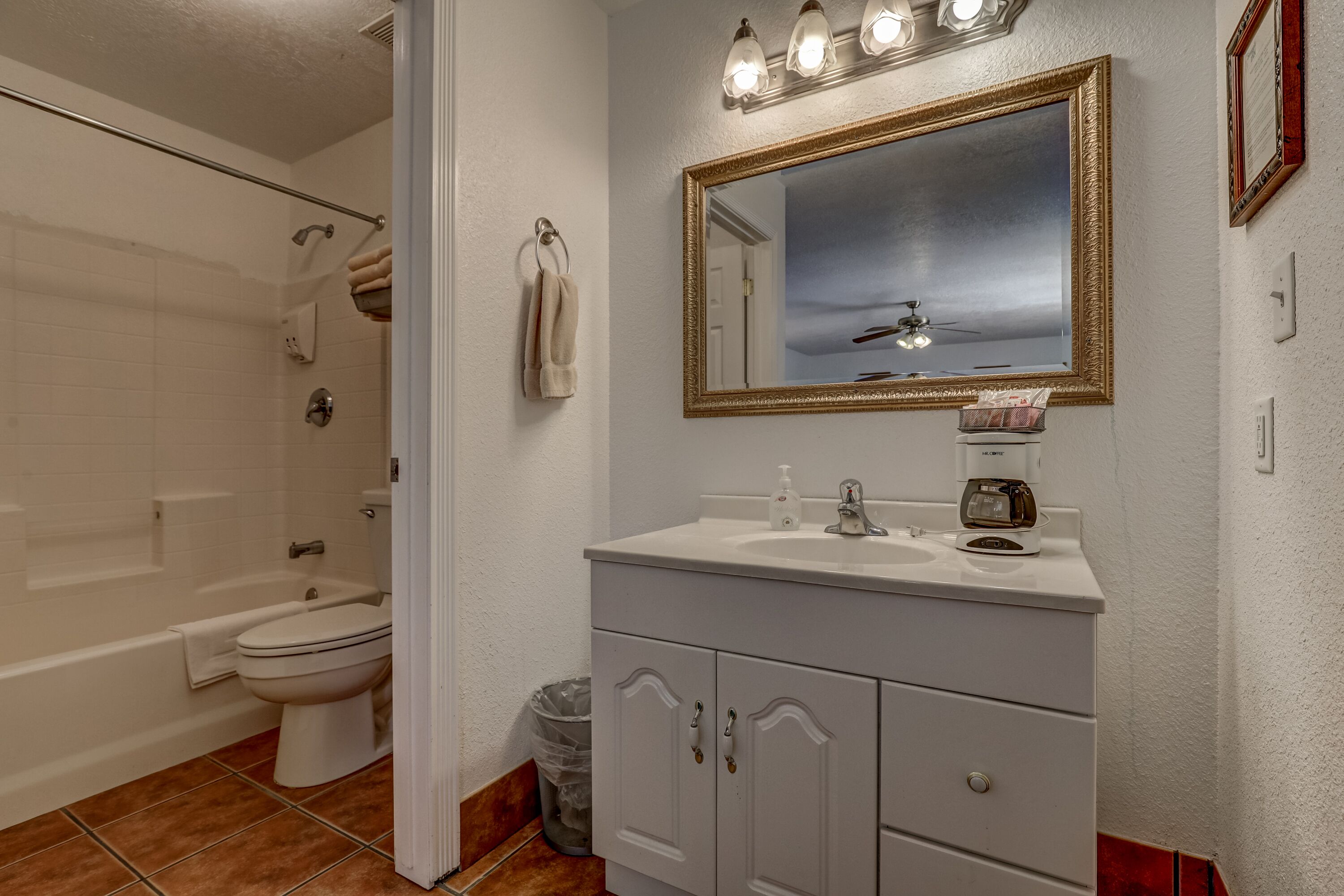 Un baño con tocador blanco, un espejo grande y zona de ducha.