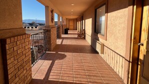A covered corridor with tiled flooring, a brick wall on one side, and a door on the other. - The Snuggle Inn (Loa)