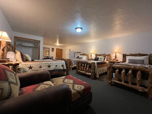 A cozy room with a large bed, a wooden headboard, a wooden chair, and a small table with a lamp.