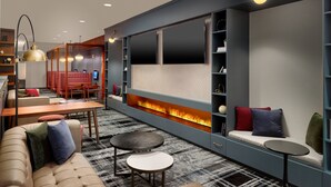A modern lounge area with a sofa, tables, a fireplace, and a TV wall.