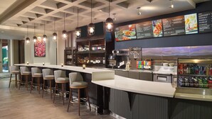 A bar area with a long counter, multiple stools, and a menu board.