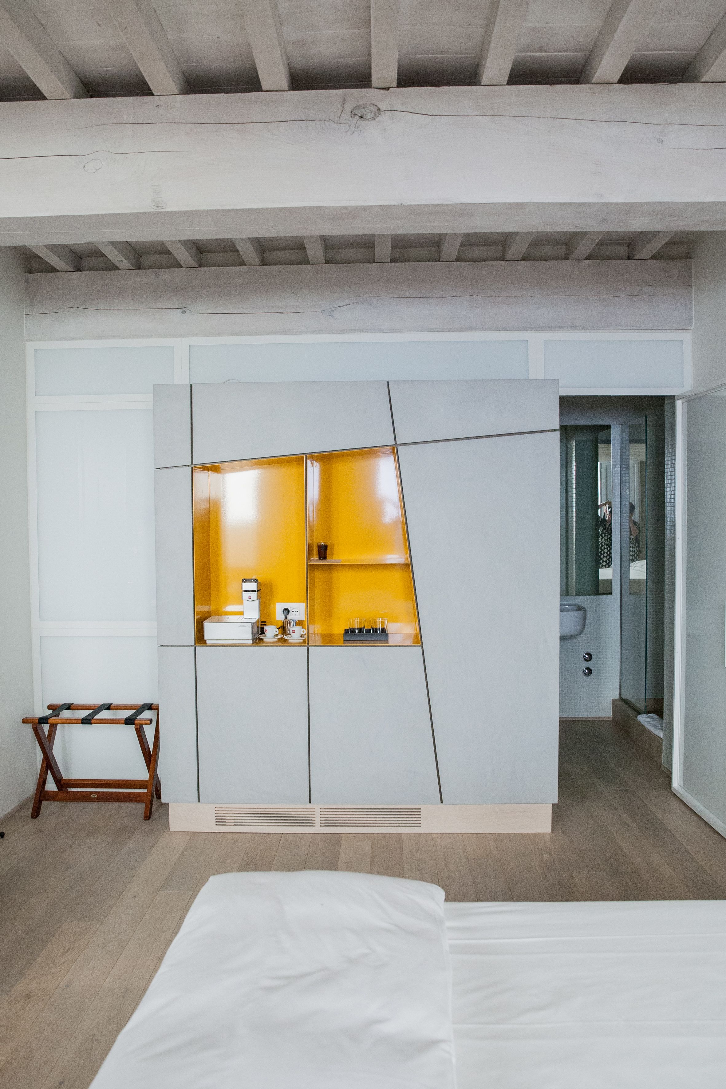 A modern bedroom with a bed, a wardrobe, and a bathroom visible through an open door.