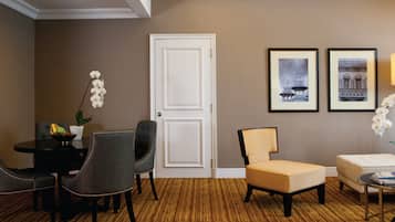 Habitación de hotel con comedor, sofá, una silla y dos cuadros en la pared.