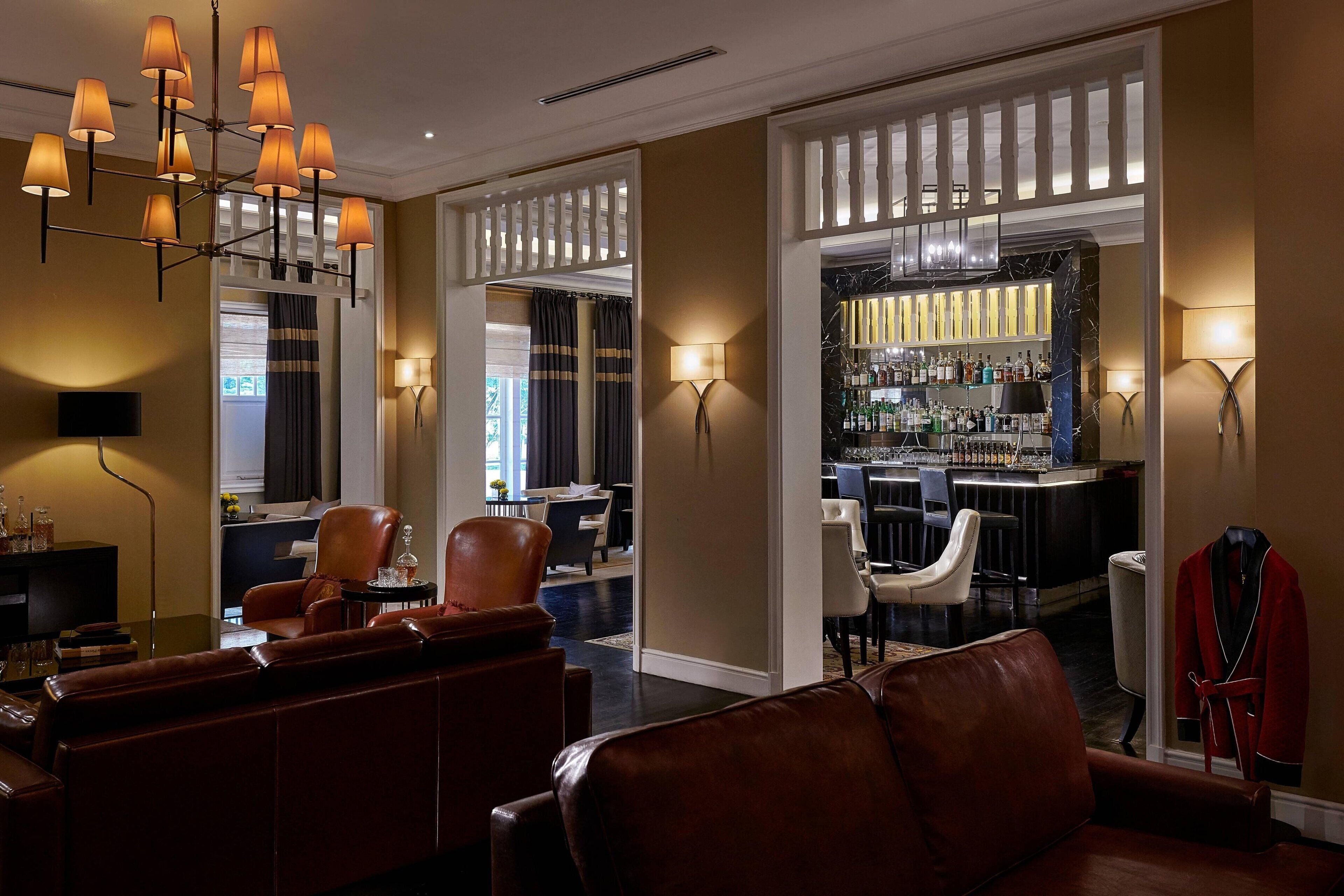 A hotel lobby with leather sofas, a bar area, and a chandelier.