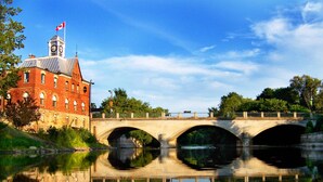A historic building with a clock tower, a bridge, and a calm river reflecting the structure. - Holiday Inn Express Pembroke by IHG (Pembroke)