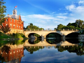 A historic building with a clock tower, a bridge, and a calm river reflecting the structure. - Holiday Inn Express Pembroke by IHG (Pembroke)