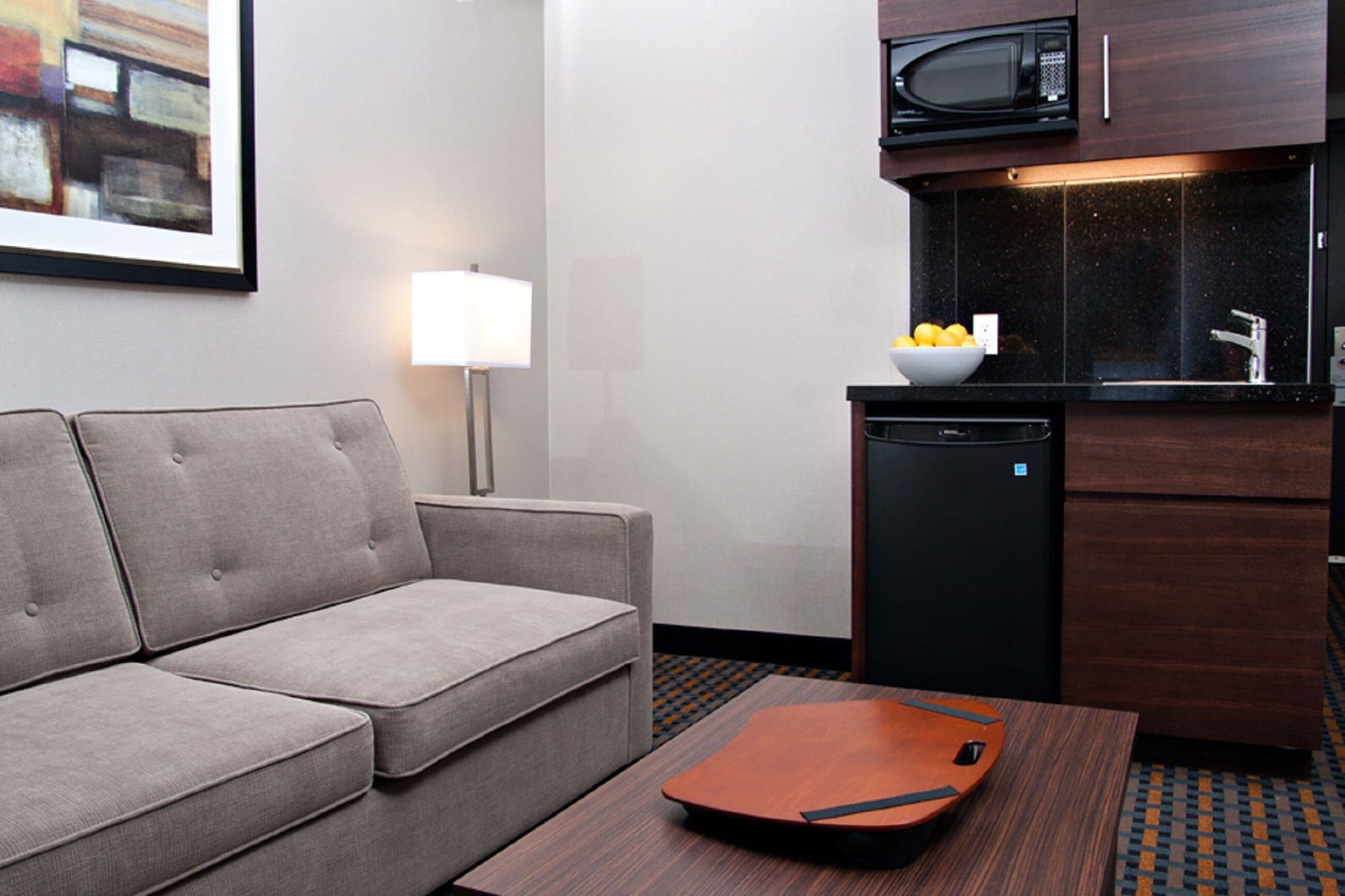 Una habitación de hotel con sofá, una mesita, microondas y lavavajillas.