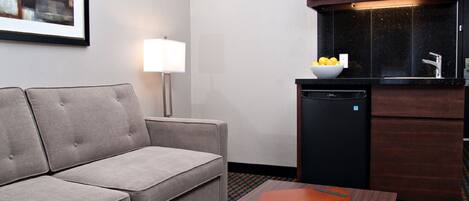 Una habitación de hotel con sofá, una mesita, microondas y lavavajillas.