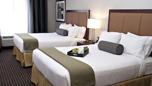Two double beds with white linens, brown headboards, and beige bed skirts. There is a tray with a bottle and glasses on the bed. - Holiday Inn Express Pembroke by IHG (Pembroke)